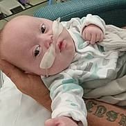Scott joined the competition — help win amazing prizes! baby, infant, hospital, medical_equipment, oxygen_tube, hand, tattoo, bed, blanket, person, face, clothing, healthcare, patient, indoor, caregiver, monitoring_device, reaching_hand, hospital_room, comfort