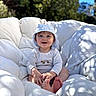 baby, child, smiling, hat, onesie, cushion, outdoor, sunlight, blue_sky, green_foliage, happy, barefoot, portrait, infant, cute, sitting, face, nature, daylight, comfortable