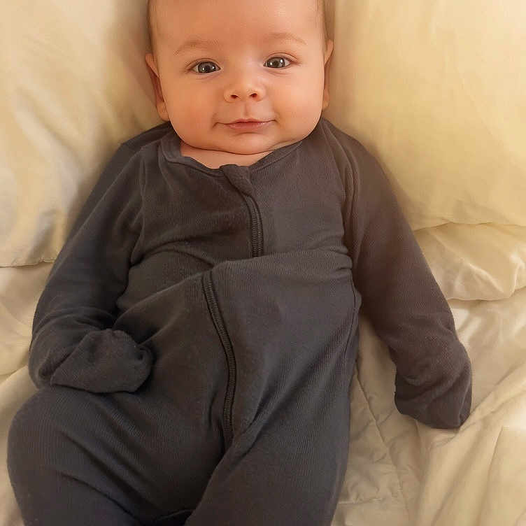 Leviticus joined the competition — help win amazing prizes! baby, infant, onesie, bed, blanket, smile, face, person, sleepwear, cute, child, lying_down, cozy, comfort, soft_light, portrait, young, indoors, skin, expression