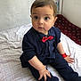 baby, child, infant, sitting, clothing, bow_tie, polka_dot, navy_blue, red, socks, wristband, bedspread, indoor, curious, face, cute, portrait, person, young_child, fashion