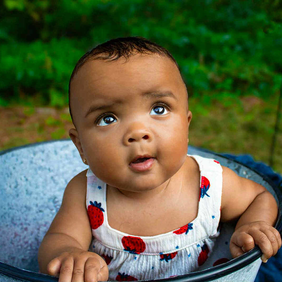 Ta'Maya joined the competition — help win amazing prizes! baby, blue_flower, bucket, child, curious, cute, face, flowers, garden, greenery, hands, infant, nature, outdoor, portrait, red_flower, skin, strawberry_pattern, summer_clothing, white_flower