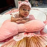 Blakelea is registered to the contest to win money with this photo: baby, infant, pink_bow, headband, plush_pillow, pink_pillow, flower_pattern, blanket, bed, cute, wide_eyes, lying_down, indoors, soft_texture, portrait, child, young, small_hands, curious, cozy