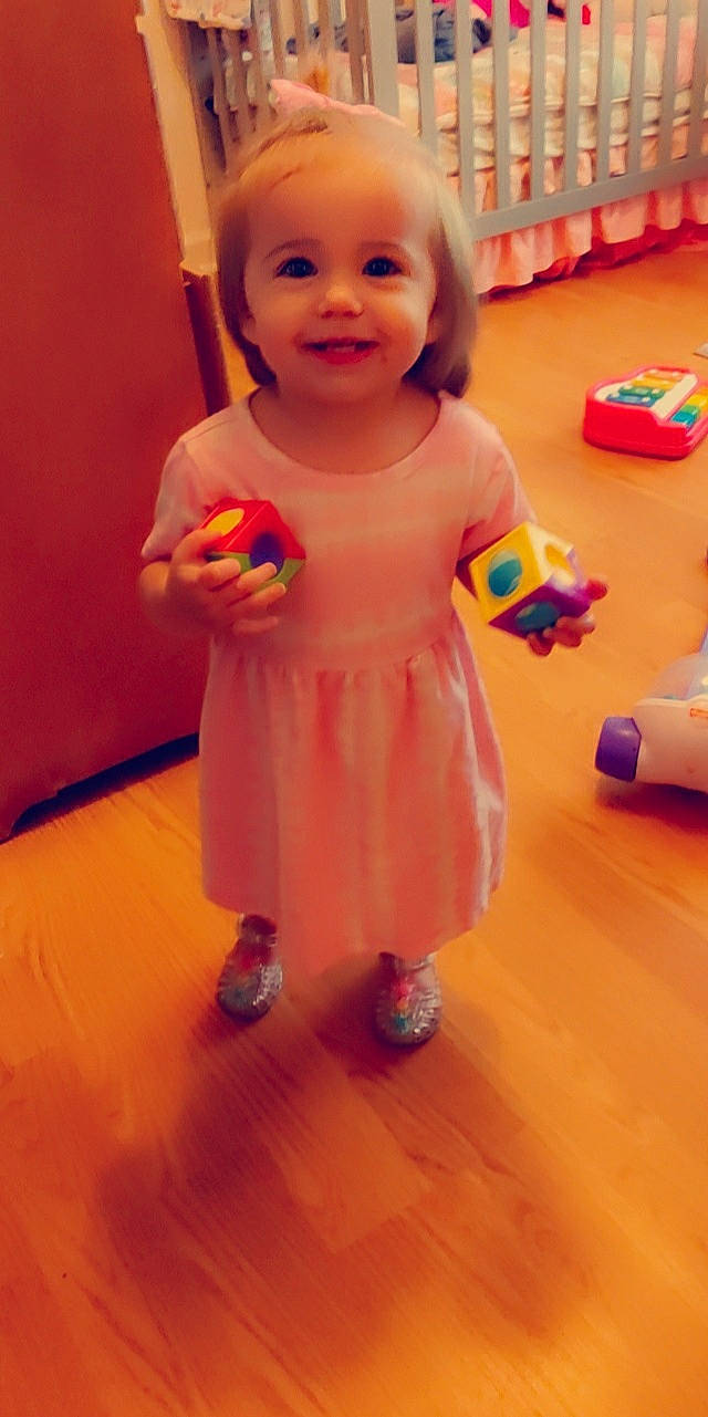 Delilah joined the competition — help win amazing prizes! baby, child, dress, facial_expression, floor, flooring, fun, happy, hardwood, human_leg, joy, leg, orange, person, pink, product, skin, smile, thumb, toddler