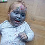 toddler, child, paint, face_paint, messy, white_clothing, wood_floor, marker, colorful, baby, hand, expression, indoor, playful, art, fun, smiling, casual, young, portrait