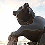 toddler, child, statue, bear, outdoor, sculpture, sky, clouds, people, playful, curious, cozy_clothing, pants, shoes, platform, daylight, large_object, public_space, buildings, casual