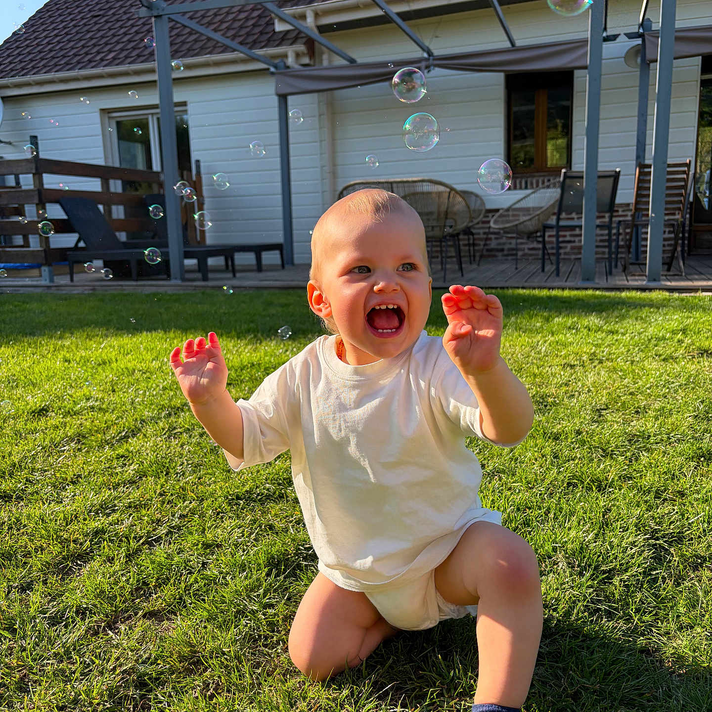 Télyo a rejoint le concours — aidez-le/la à gagner de superbes lots ! toddler, child, grass, bubbles, outdoor, smiling, sunlight, house, patio, white_shirt, sock, playtime, happy, daytime, greenery, baby, lawn, kneeling, joy, summer