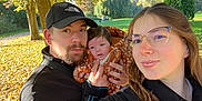 Ana participe au concours pour gagner de l'argent avec cette photo : family, baby, man, woman, glasses, cap, outdoor, park, autumn, leaves, trees, sunlight, jacket, smile, nature, greenery, portrait, holding, people, daylight