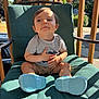 toddler, child, outdoor, sunlight, green_chair, grey_tshirt, blue_shoes, wooden_railing, smiling, sitting, playful, daylight, person, portrait, baby, casual_clothing, home, summer, cute, relaxed