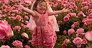 Mika is registered to the contest to win money with this photo: child, girl, rose_field, pink_dress, flower_petals, sunset, nature, smiling, joyful, outdoor, greenery, veil, barefoot, plants, flower, portrait, happiness, spring, blossom, scenery