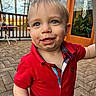 toddler, child, boy, red_shirt, blue_eyes, smiling, outdoor, patio, brick_floor, wooden_railing, door, glass, daylight, happy, messy_face, casual_clothing, person, young_child, cute, portrait