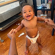 Amirion is registered to the contest to win money with this photo: baby, toddler, diaper, smiling, happy, indoor, wooden_floor, hands, support, walking, person, child, jewelry, necklace, bracelet, furniture, chair, table, floor, home
