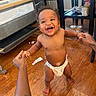 baby, toddler, diaper, smiling, happy, indoor, wooden_floor, hands, support, walking, person, child, jewelry, necklace, bracelet, furniture, chair, table, floor, home