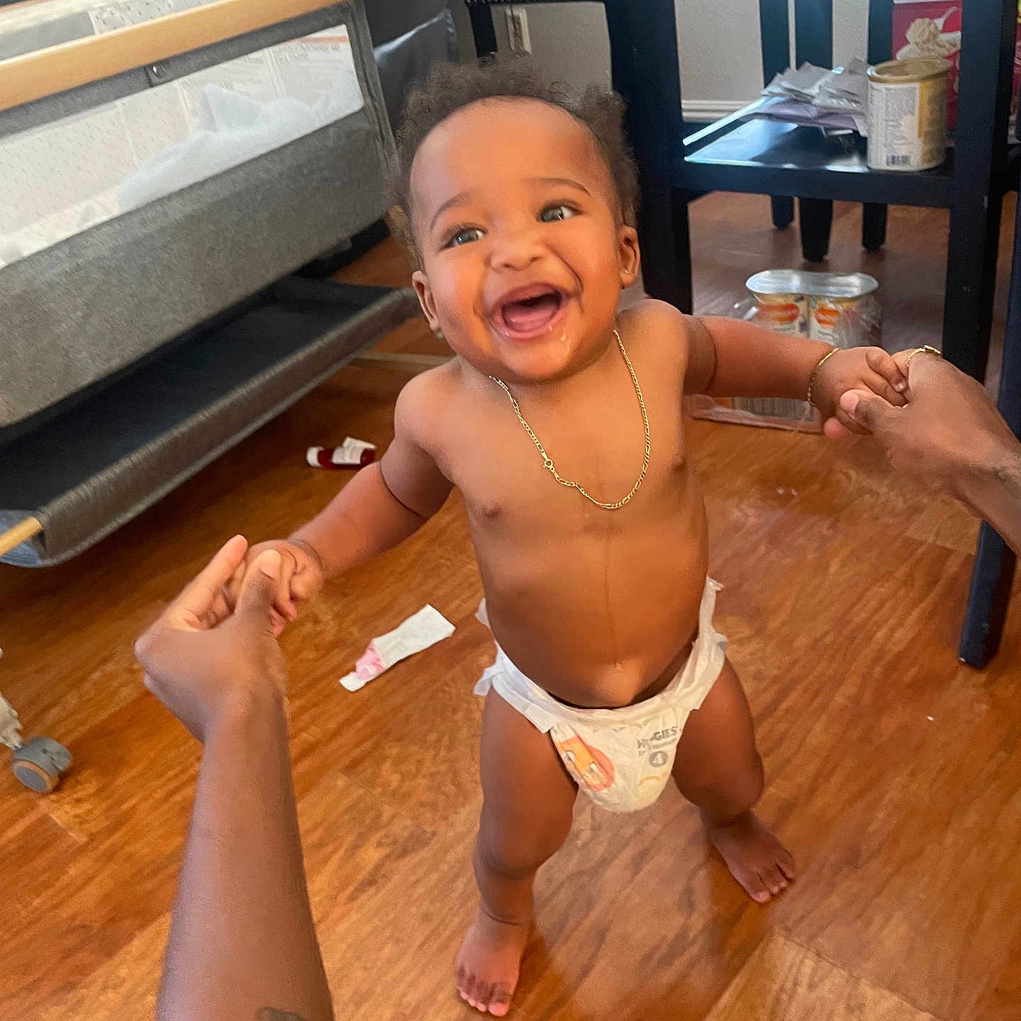 Amirion is registered to the contest to win money with this photo: baby, toddler, diaper, smiling, happy, indoor, wooden_floor, hands, support, walking, person, child, jewelry, necklace, bracelet, furniture, chair, table, floor, home