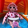 baby, child, inflatable_pool, water, sunglasses, heart_shaped_glasses, swimsuit, strawberry_pattern, hat, pink, orange, toy_ball, summer, outdoor, splashing, sun_protection, cute, playtime, infant, canopy