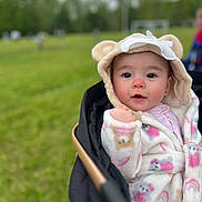 Jocelyn joined the competition — help win amazing prizes! baby, child, hood, coat, stroller, outdoor, grass, field, face, cute, infant, warm_clothing, pink, white, animal_ears, portrait, young_child, expression, nature, daytime