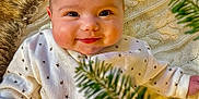 Athena joined the competition — help win amazing prizes! baby, cheeks, child, closeup, cozy, cute, eyes, face, fur_texture, happy, indoors, infant, knitted_blanket, pine_branches, portrait, smiling, soft_lighting, stars_pattern, warm_colors, white_clothing