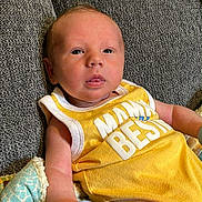 Landen is registered to the contest to win money with this photo: baby, infant, newborn, onesie, yellow_onesie, mitten, couch, sofa, blanket, upholstery, face, eyes, mouth, skin, hair, portrait, indoors, relaxing, comfort, baby_clothing