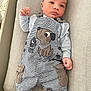 Owen a rejoint le concours — aidez-le/la à gagner de superbes lots ! baby, infant, child, overalls, striped_clothing, dog_design, plush_surface, barefoot, relaxed, portrait, cute, small_hands, small_feet, lying_down, indoors, soft_texture, casual_clothing, young_child, curious_expression, infant_wear