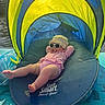 Vienna joined the competition — help win amazing prizes! baby, sunglasses, pacifier, beach_gear, float, canopy, yellow, blue, striped_clothing, hat, sun_protection, water, outdoor, relaxing, summer, vacation, infant, legs, person, shade