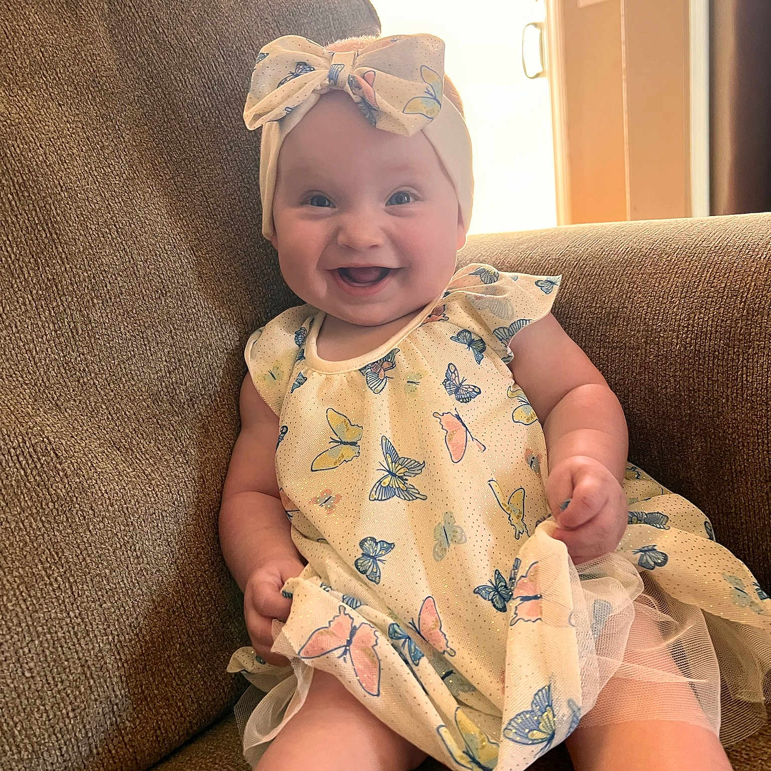 Vienna joined the competition — help win amazing prizes! baby, child, smiling, dress, headband, bow, butterfly_pattern, couch, indoor, happy, person, infant, sitting, sunlight, warm_light, cute, portrait, fabric, furniture, skin