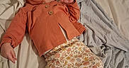 Magdalen is registered to the contest to win money with this photo: baby, sleeping, bed, blanket, clothing, floral_pattern, hoodie, infant, indoors, peaceful, person, pajamas, resting, soft_fabric, toddler, white_sheet, lying_down, cute, cozy, child