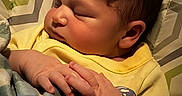 Emiliano is registered to the contest to win money with this photo: newborn, baby, infant, sleeping, peaceful, portrait, close_up, face, hands, yellow_outfit, blanket, bedding, cozy, indoors, resting, curly_hair, closed_eyes, photography, patterned_background, family