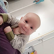 Malone a rejoint le concours — aidez-le/la à gagner de superbes lots ! baby, bedroom, cleaning_tool, clothing, cute, door, fabric, face, floor, head, indoor, infant, mop, onesie, person, purple, smile, toy, white_wall, young_child