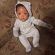 Zymir joined the competition — help win amazing prizes! baby, child, infant, portrait, sitting, couch, sofa, hoodie, onesie, gray_clothing, bear_ears, gap_logo, wide_eyes, facial_expression, indoor, home, furniture, textile, patterned_background, photography