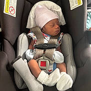 Brinson is registered to the contest to win money with this photo: newborn, baby, car_seat, chicco, infant, hat, mittens, socks, sleeping, straps, safety, seat_belt, child, clothing, fabric, comfort, indoor, resting, person, cute