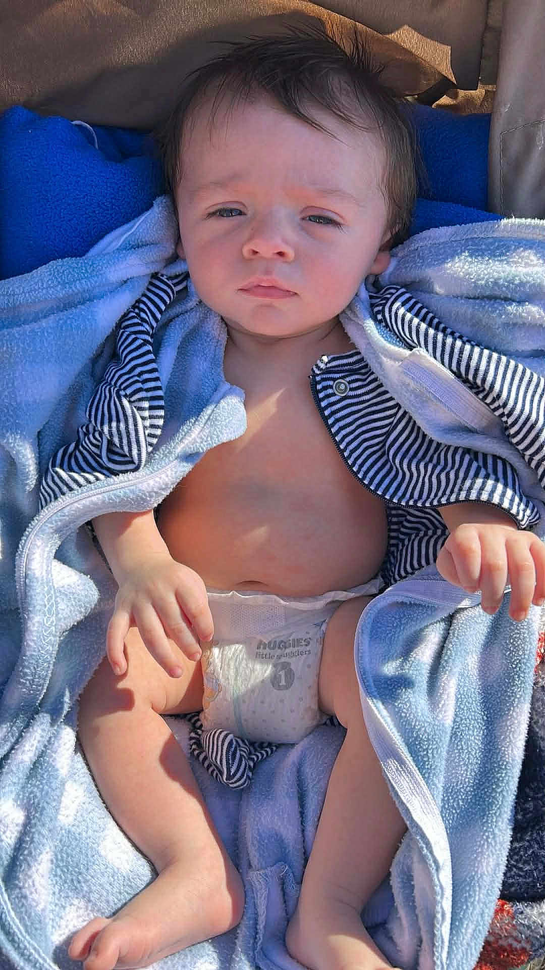 Judah is registered to the contest to win money with this photo: baby, infant, child, diaper, blanket, towel, striped_clothing, face, eyes, hair, hands, feet, stroller, sunlight, outdoor, portrait, blanket_wrap, candid, relaxed, cute