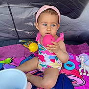 Thalia participe au concours pour gagner de l'argent avec cette photo : toddler, child, swimsuit, headband, toy, ball, pink_ball, yellow_ball, giraffe_toy, colorful_towel, bucket, indoor, sitting, curious, playtime, baby, person, cute, summer, play