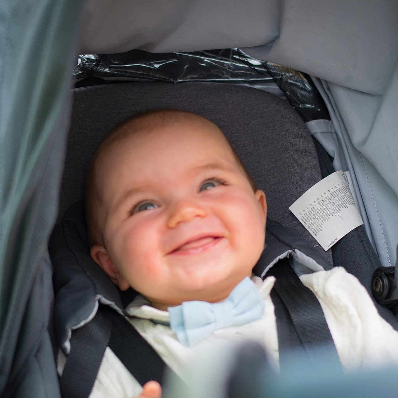 Léo a rejoint le concours — aidez-le/la à gagner de superbes lots ! baby, baby_boy, bow_tie, canopy, child, closeup, clothing, cute, fabric, face, happy, head, infant, outdoor, person, portrait, seat, seatbelt, smiling, stroller
