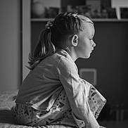 Ambre participe au concours pour gagner de l'argent avec cette photo : child, girl, bedroom, black_and_white, profile, braided_hair, ponytail, pajamas, patterned_pants, sitting, bed, soft_lighting, indoors, contemplative, young, portrait, furniture, blurred_background, casual_clothing, home