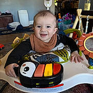 Arthur joined the competition — help win amazing prizes! baby, child, smile, piano, toy, activity_center, indoor, colorful, face, clothing, hand, floor, carpet, furniture, playtime, infant, happy, living_room, footwear, baby_bib