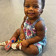 Melody joined the competition — help win amazing prizes! toddler, child, smiling, sitting, floor, toy, remote_control, sandals, floral_dress, earring, happy, cute, indoor, person, baby, skin, arm, leg, face, eyes