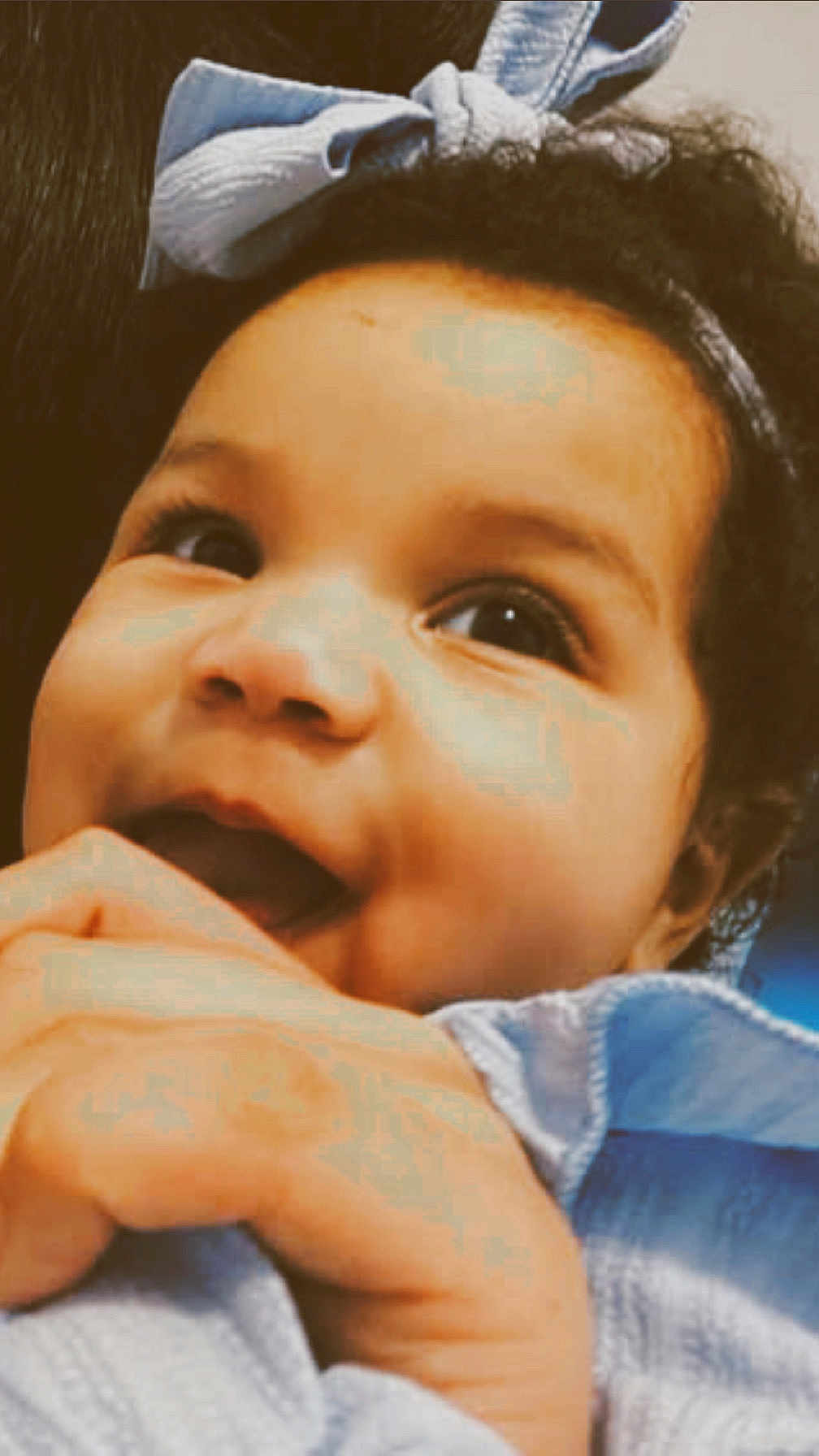 Stori joined the competition — help win amazing prizes! baby, child, face, curly_hair, blue_bow, hand, fingers, clothing, closeup, cute, infant, portrait, smiling, happy, young_child, indoor, skin, person, head, expression