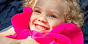 Kelly is registered to the contest to win money with this photo: child, girl, smiling, curly_hair, blonde, pink_dress, outdoor, blanket, happy, face, portrait, cute, joyful, childhood, fashion, person, lying_down, playful, sunlight, accessory