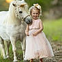 child, pony, unicorn_horn, pink_dress, girl, outdoor, nature, grass, happy, smiling, animal, horse, curly_hair, bow, portrait, friendship, summer, cute, pet, fairytale