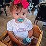Michaela joined the competition — help win amazing prizes! toddler, child, pacifier, baby_bottle, high_chair, pink_bow, white_shirt, indoor, restaurant, wooden_chair, curious, person, baby, table, floor, seat, clothing, cute, dining, young_child