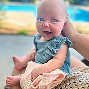 Emma joined the competition — help win amazing prizes! baby, blue_eyes, smiling, happy, infant, child, blanket, hand, outdoor, pool, greenery, summer, cute, portrait, person, clothing, skin, sitting, holding, soft_focus