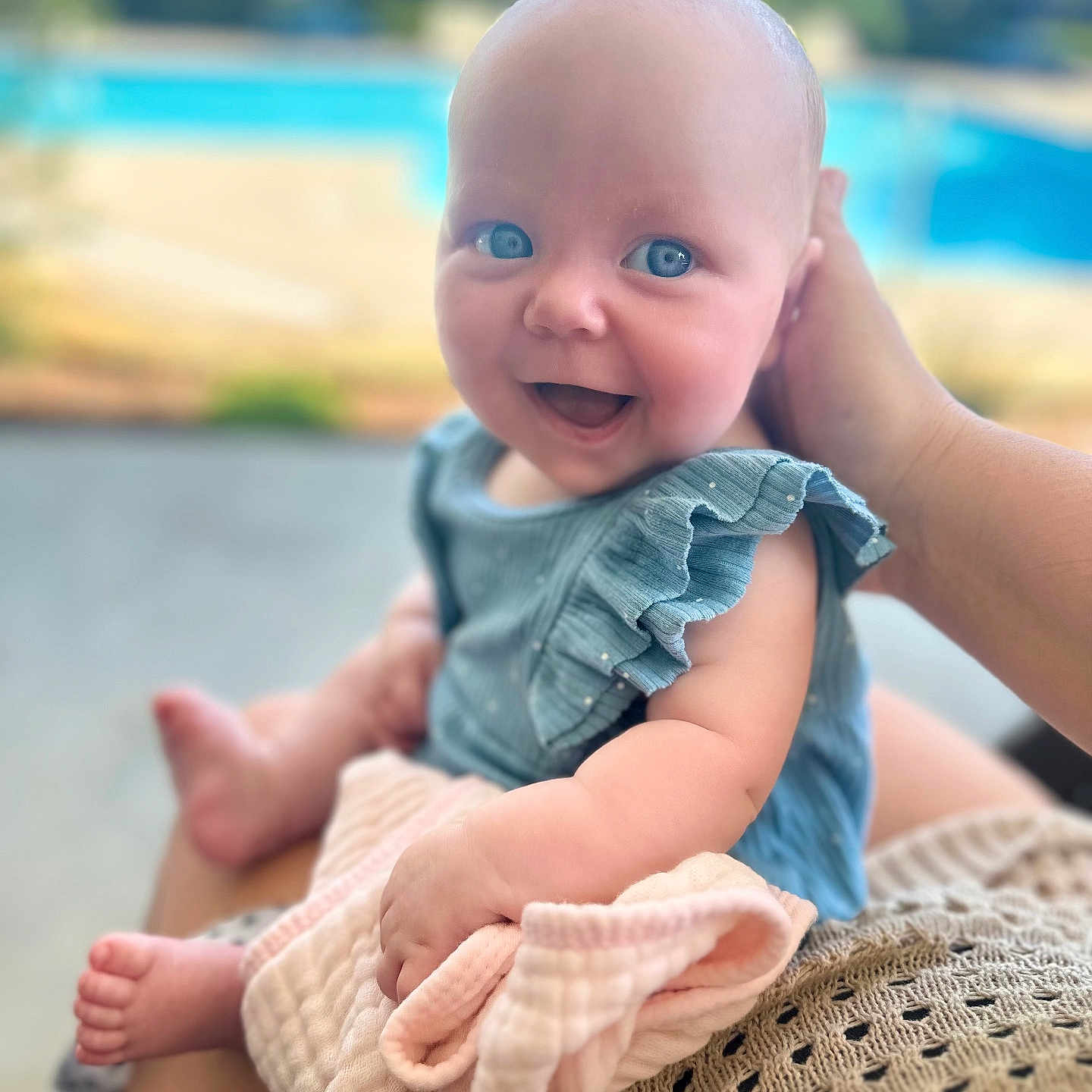 Emma joined the competition — help win amazing prizes! baby, blue_eyes, smiling, happy, infant, child, blanket, hand, outdoor, pool, greenery, summer, cute, portrait, person, clothing, skin, sitting, holding, soft_focus