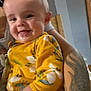 baby, child, smile, yellow_clothing, floral_pattern, drool, tattoo, bracelets, arm, indoor, person, happy, face, infant, cute, holding, closeup, portrait, skin, head