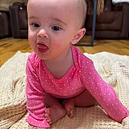 Stormy is registered to the contest to win money with this photo: baby, child, infant, pink_clothing, polka_dot, blanket, floor, indoor, furniture, living_room, tongue_out, cute, sitting, crawling, head, face, human, skin, foot, hand
