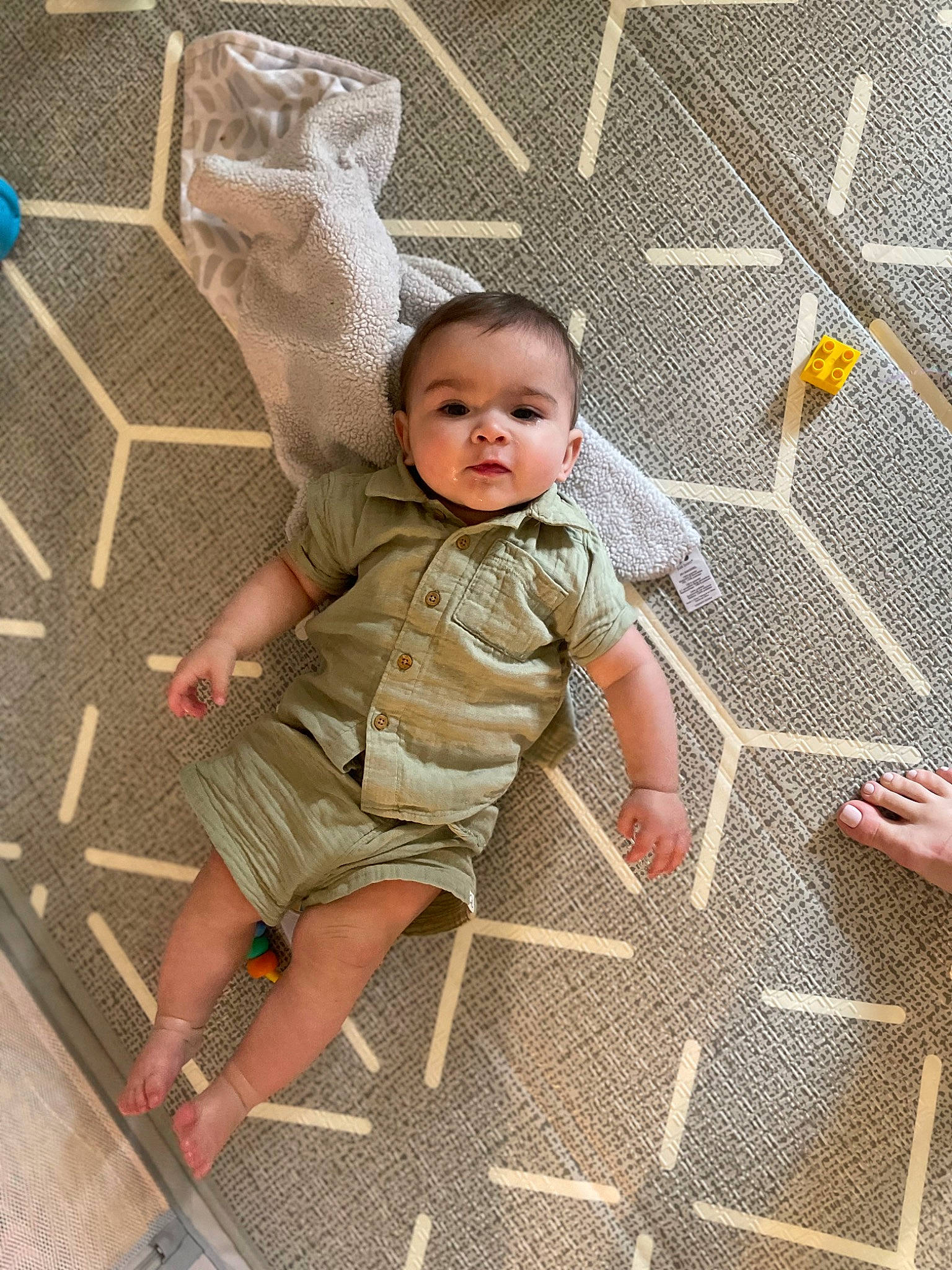 Aidan is registered to the contest to win money with this photo: baby, baby_products, baby_toddler_clothing, barefoot, child, dress, floor, flooring, foot, fun, human_leg, leisure, pattern, person, play, sandal, sitting, skin, toddler, wood