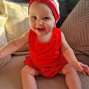Lyana participe au concours pour gagner de l'argent avec cette photo : baby, child, smiling, red_clothing, headband, sitting, couch, cushion, happy, indoors, footwear, shoes, cute, person, portrait, infant, skin, furniture, closeup, young