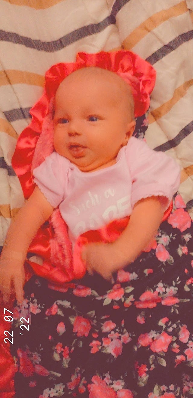 Averie is registered to the contest to win money with this photo: baby, baby_products, baby_toddler_clothing, cheek, child, chin, comfort, dress, finger, happy, iris, lip, magenta, pattern, peach, person, pink, skin, sleeve, textile