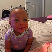 Kloie joined the competition — help win amazing prizes! child, baby, toddler, smiling, portrait, indoor, bedroom, pillow, blanket, hair_buns, onesie, baby_brush, foot, toes, cute, infant, face, bed, door, bedding