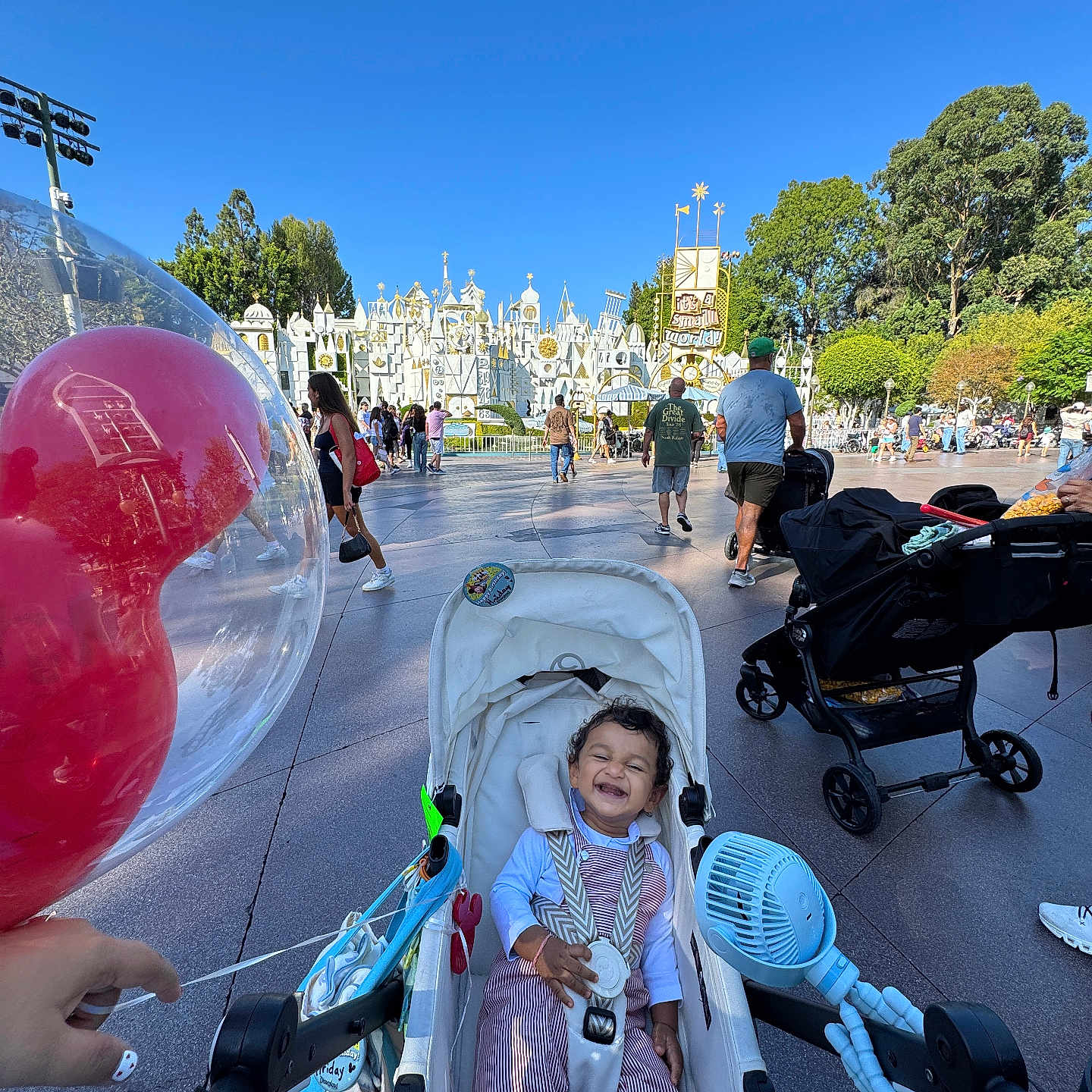 Hriday Ram joined the competition — help win amazing prizes! amusement_park, baby, balloon, blue_sky, child, crowd, family, fan, infant, outdoor, park, portrait, ride, seated, smiling, stroller, sunny, toy, travel, trees