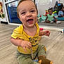 Kasen joined the competition — help win amazing prizes! toddler, baby, child, smiling, sitting, yellow_shirt, green_pants, pacifier_clip, mirror, reflection, playroom, floor, toy, indoor, happy, cute, childcare, infant, casual_clothing, playful