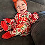 Kenadi is registered to the contest to win money with this photo: baby, child, smiling, onesie, headwrap, orange, pumpkin, couch, happy, infant, sitting, clothing, cute, portrait, indoor, face, hand, footwear, cozy, expression